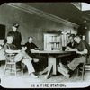 Fire house : men in a firehouse sitting around table reading, case for Traveling Library between them