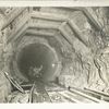 Rondout pressure tunnel. Completed excavation with temporary roof timbering in place. Finished concrete lining in background. Contract 12. April 21, 1911.
