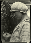 Woman in mob cap, with knitting yarn on a reel in the background