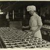Woman in a mob cap sorting chocolates into wooden boxes]