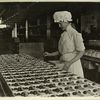 Woman in a mob cap sorting chocolates into wooden boxes