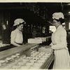 Two women sort chocolates, facing each other]