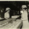 Two women sort chocolates, facing each other