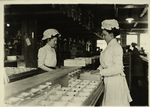 Two women sort chocolates, facing each other