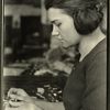 Woman worker appears to be pulling the woven tube of cloth used for insulating wires over the bare wire