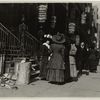 Group of women workers gathered on sidewalk in front of seveal millinery establishments