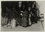 Group of women workers gathered on sidewalk in front of seveal millinery establishments