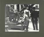 ... this bootblack keeps his mind on his job, July 1910
