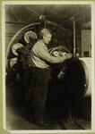 Man standing at machine with disks and webbed belt