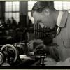 Precision tool making, worker is making close adjustments before pushing the piece against the lathe