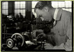 Precision tool making, worker is making close adjustments before pushing the piece against the lathe