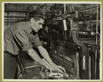 Workman replacing an empty shuttle with a full one in this power loom