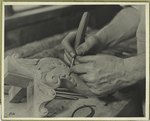 Hands of a wood carver putting finishing touches on a Chippendale chair or table leg