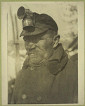 Miner in overcoat with cap and light.
