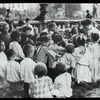 Work with schools, Hudson Park Branch : children gathered around librarian who is reading in the park, ca. 1910s