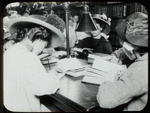 Work with schools : writing a composition : girls each wearing straw hat, bent over their work, ca. 1910s