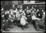 Work with schools : a librarian's assistant telling a story to a group of Russian children in their native language, ca. 1910s
