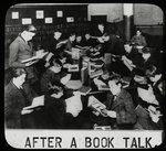 Work with schools : after a book talk, showing boys gathered around table reading, ca. 1920s.