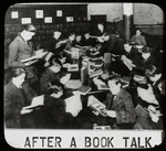 Work with schools : after a book talk, showing boys gathered around table reading, ca. 1920s