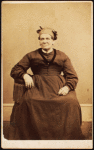 Portrait of seated woman wearing a headwrap.