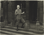 Bernard Shaw on the steps with a news-paper in his hands.