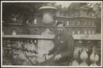 Richard Aldington sitting on a chair in the street