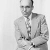 Potrair of Kurt Weill (with spectacles, tie, hands folded in lap)