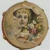 A trade card depicting a girl's face framed by a tambourine and flowers.