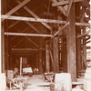 Interior work : barrels, wheelbarrows and a cart beneath wooden scaffolding