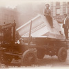 Two men with a block of marble on a cart