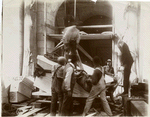 Group of workers tying ropes around a block of marble