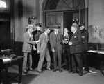 Scene from The Front Page (by) Hecht & MacArthur. NYC.1928. Osgood Perkins as Walter Burns (extreme left wearing homburg) and Lee Tracy (Hildy Johnson) 3rd from left, next to policeman, without hat.