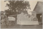 Josephine Cogdell, age eight, as the queen of a reunion gathering, seated at far right on a float sponsored by Haralson's Dry Goods Company, Texas, ca. 1908. The African American man handling the horse team pulling the float is identified as Dip