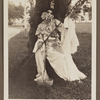 Edith James Long outdoors wearing Chinese costume and leaning against a tree.