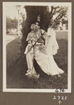 Edith James Long outdoors wearing Chinese costume and leaning against a tree.