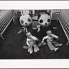 Twin boys with bottles and large stuffed panda bears