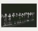 Cast members in line on stage holding headshots in front of their faces in the stage production of A Chorus Line.