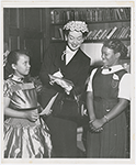 Actress Rosalind Russell, with two students from the St. Charles Parochial School, attending the Second Annual Tea of the St. Charles Women's Auxiliary, held at the Duchesne Residence School, in New York City, in May 1953. Ms. Russell, with three others, received awards for their contributions in the field of Human Relations