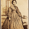 Portrait of young woman wearing patterned dress, with bow at neck.
