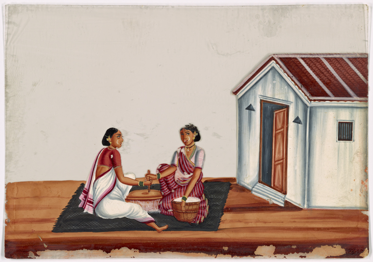 Two women sitting in front of baskets, on black rug in front of white ...