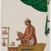 Seated male butcher with meat hanging on hooks, in front of a goat head