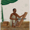 Seated male carpenter sawing a wood board, with tools on the ground