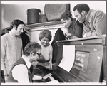Peter Udell [standing left], Gary Geld [seated at piano], Melba Moore [second from right leaning on piano], Cleavon Little [right leaning on piano] and unidentified [holding pen looking at Gary Geld] in rehearsal for the stage production Purlie