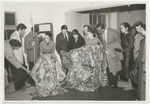Martha Graham and dancers dressed in street clothes looking at two elaborate kimonos