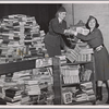 Two girls loading books collected in New York Victory Campaign into handtruck in preparation of shipment to the USO Clubs.