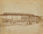 Elevated railroad curve & train; men working on streetcar tracks