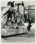 Nora Kaye and a group of female dancers of American Ballet Theatre posing in front of a plane at Idlewild Airport, 1958