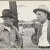 Two men in conversation with a lumber yard in the background?