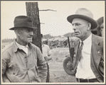 Two men in conversation with a lumber yard in the background?