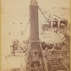 The crated obelisk "Cleopatra's Needle" secured by ropes to machinery prior to being lowered to a horizontal position 